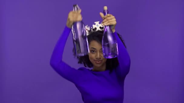 hymyilevä afrikkalainen amerikkalainen nainen tanssii pullot eristetty violetti
  - Materiaali, video