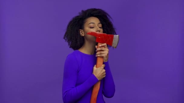 mujer afroamericana sosteniendo hacha y sonriendo aislado en púrpura
  - Metraje, vídeo