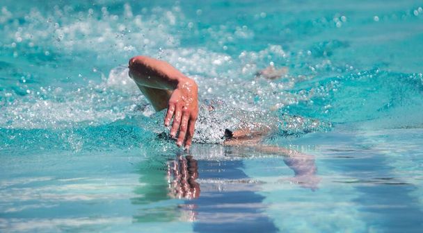 Selektivní zaostření snímku člověka plavání ve vodě s vodou stříkající kolem - Fotografie, Obrázek