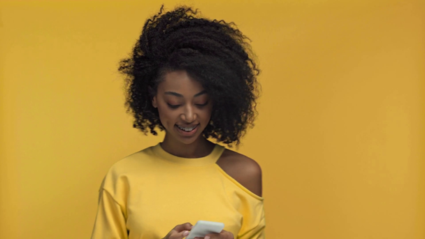 усміхнена афроамериканська жінка бере селфі ізольовано на жовтому
 - Кадри, відео