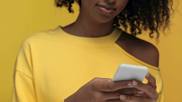 黄色で隔絶されたスマートフォンでアフリカ系アメリカ人女性を切り取り - 映像、動画