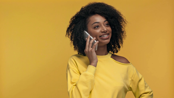 sorrindo mulher afro-americana falando no smartphone isolado no amarelo
 - Filmagem, Vídeo