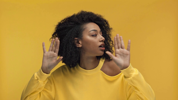 mujer afroamericana escuchando y sonriendo aislada en amarillo
 - Imágenes, Vídeo