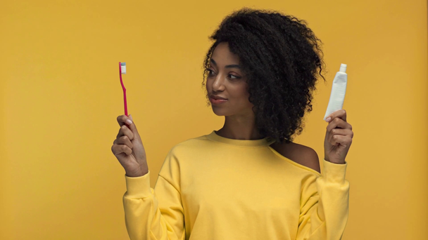 femme afro-américaine choquée tenant dentifrice et brosse à dents isolés sur jaune
 - Séquence, vidéo