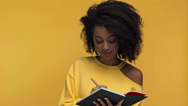 sonriente afroamericana mujer escribiendo y hablando aislado en amarillo
 - Imágenes, Vídeo