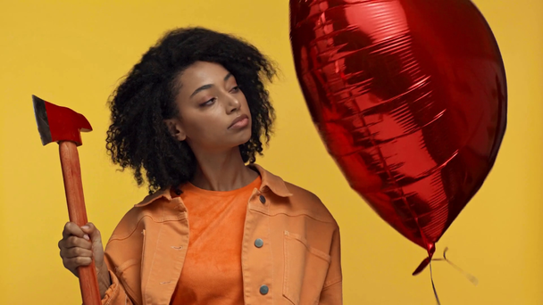 Африканская американка держит воздушный шар и топор изолирован на желтый
 - Кадры, видео
