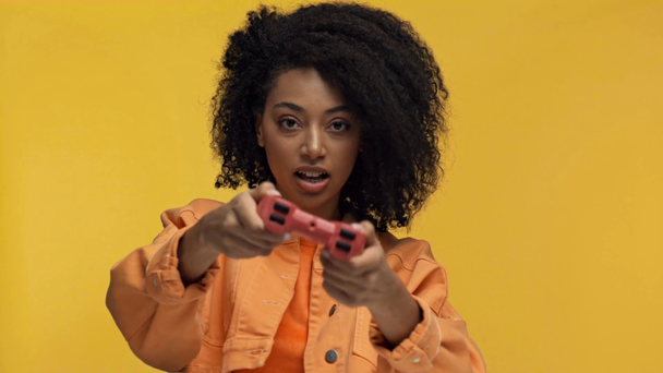 KYIV, UKRAINE - NOVEMBER 7, 2019: african american woman playing with gamepad isolated on yellow - Materiał filmowy, wideo