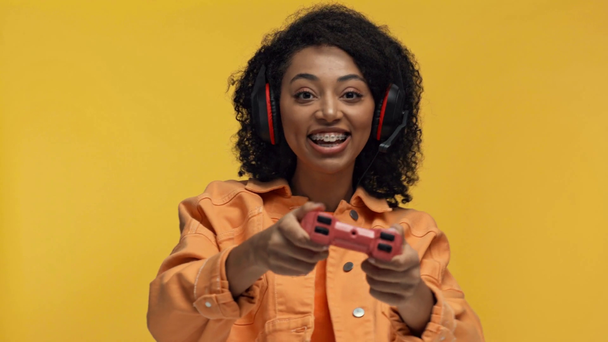 Kyiv, Ukrayna - 7 Kasım 2019: Sarı üzerinde video oyunu oynayan gülümseyen Afrikalı Amerikalı kadın - Video, Çekim