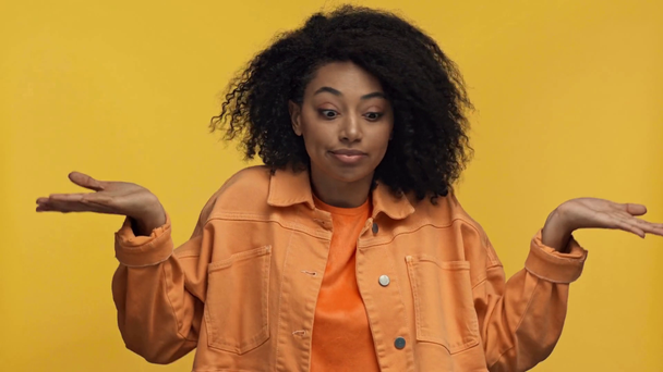 podrażniona Afroamerykanka wykazująca wzruszający gest odizolowana na żółto - Materiał filmowy, wideo