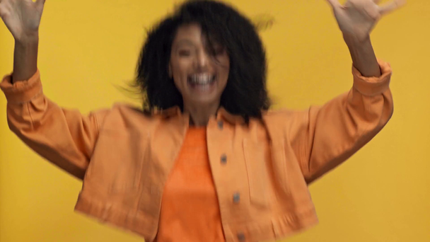 überrascht afrikanisch-amerikanische Frau winkt isoliert auf gelb - Filmmaterial, Video