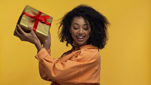 sorridente donna afro-americana in possesso di dono isolato su giallo
 - Filmati, video