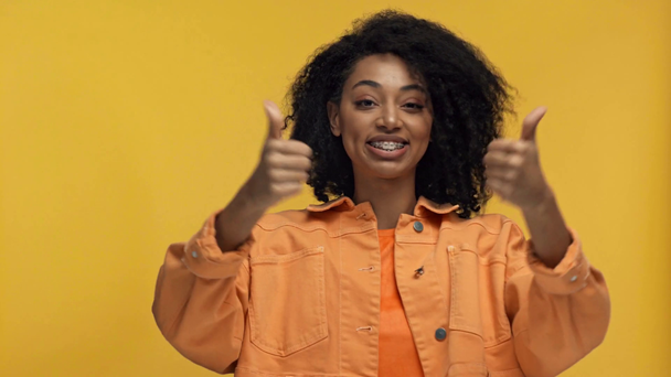 sorridente afro-americana apontando com as mãos isoladas no amarelo
 - Filmagem, Vídeo
