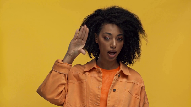 dissatisfied african american woman showing blah blah gesture isolated on yellow - Felvétel, videó