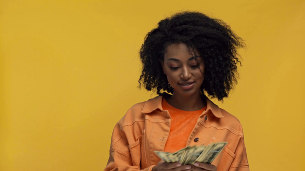 χαμογελαστή Αφροαμερικανή γυναίκα που μετράει χρήματα απομονωμένα στο κίτρινο - Πλάνα, βίντεο