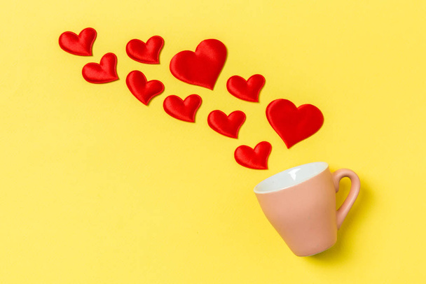 Top view of red textile hearts splashing out of a cup on colorful background. Happy Valentine's day concept - Фото, изображение