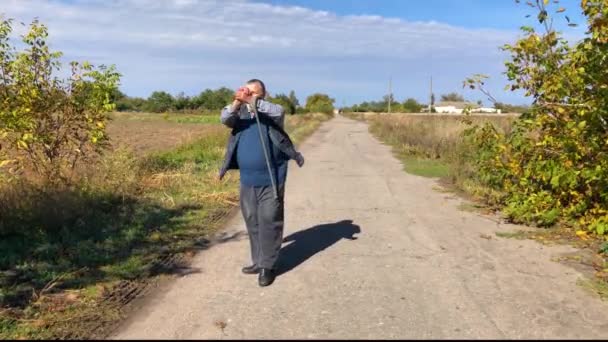 ukrainischer Bauer geht nach Abschied gestikulierend auf Landstraße - Filmmaterial, Video