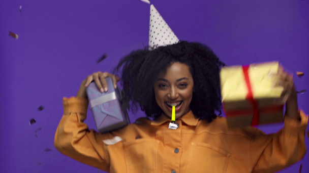 african american woman blowing in party horn isolated on purple  - Footage, Video
