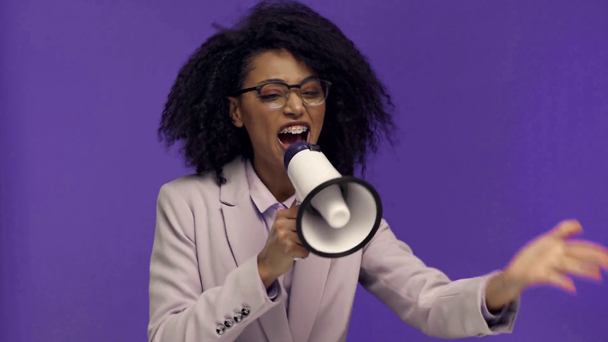 enojada mujer de negocios afroamericana gritando con un altavoz aislado en púrpura
  - Imágenes, Vídeo