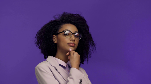 sorridente mulher de negócios afro-americana flertando isolado em roxo
  - Filmagem, Vídeo