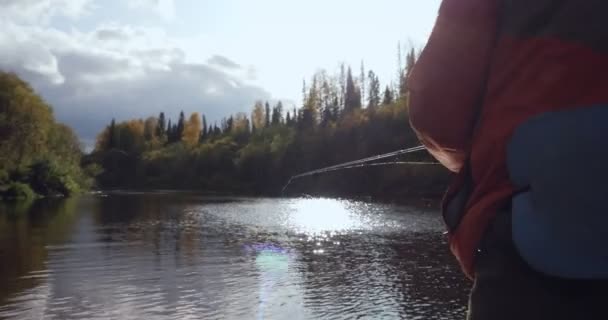 Achteraanzicht op visser gooit een hengel in de rivier. - Video