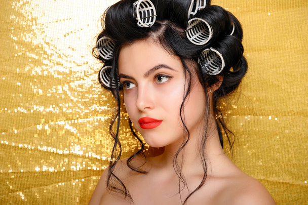 Beautiful girl in hair curlers isolated on gold - Фото, зображення