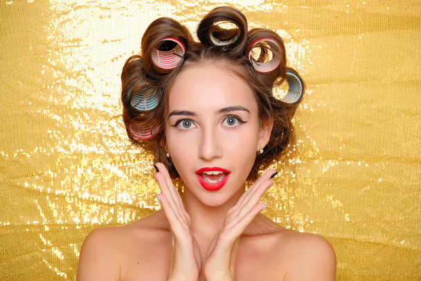 Beautiful girl in hair curlers isolated on gold - Φωτογραφία, εικόνα