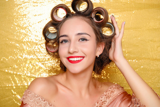 Beautiful girl in hair curlers isolated on gold - Фото, зображення