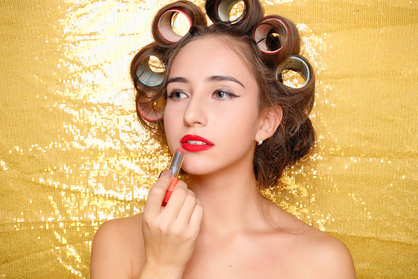 Beautiful girl in hair curlers isolated on gold - Foto, imagen