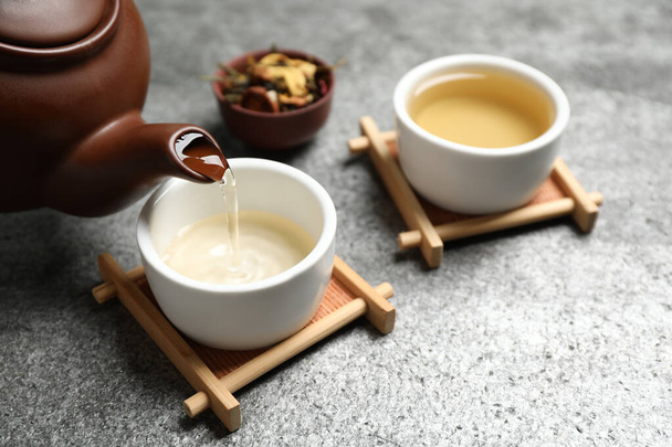 Pouring green tea into cup on grey table - Foto, imagen
