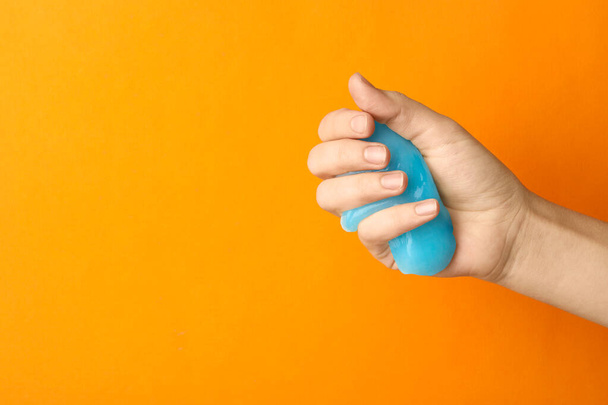 Woman playing with light blue slime on orange background, closeu - 写真・画像