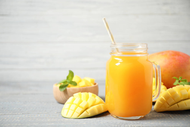 Fresh delicious mango drink on wooden table. Space for text - Φωτογραφία, εικόνα