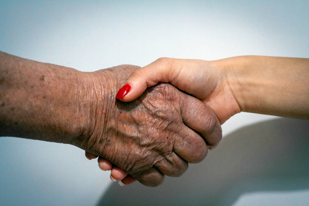 Старі і молоді жінки тримаються за руки
 - Фото, зображення