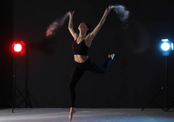 Professional acrobat with chalk powder exercising in dark studio - Zdjęcie, obraz