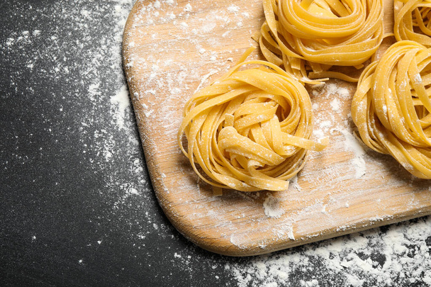 Tagliatelle pasta on wooden board, above view - 写真・画像