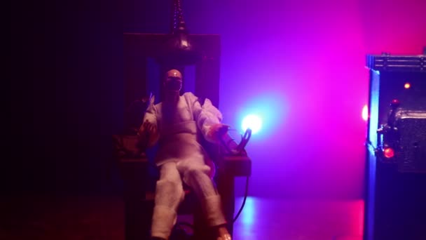 Miniatura krzesła elektrycznego kary śmierci po ciemku. Dekoracja dzieł sztuki. Obraz modelu skali krzesła elektrycznego na ciemnym grzbiecie - Materiał filmowy, wideo