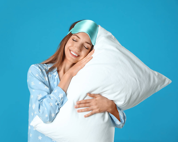Beautiful woman with pillow on light blue background. Bedtime - Foto, afbeelding