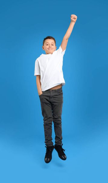 Preteen boy jumping on light blue background - Фото, зображення