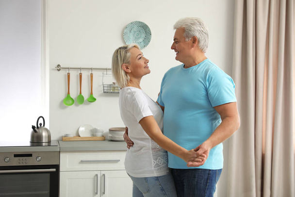 Happy mature couple dancing together in kitchen - Zdjęcie, obraz