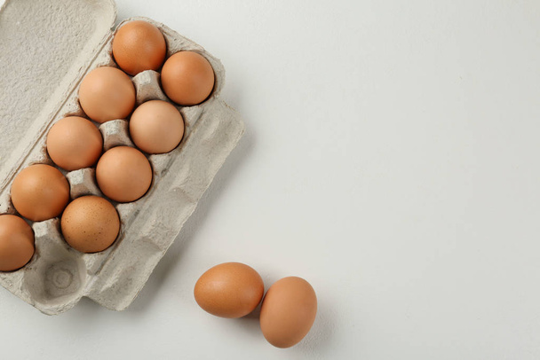 Huevos de pollo crudos en la mesa blanca, puesta plana. Espacio para texto
 - Foto, imagen