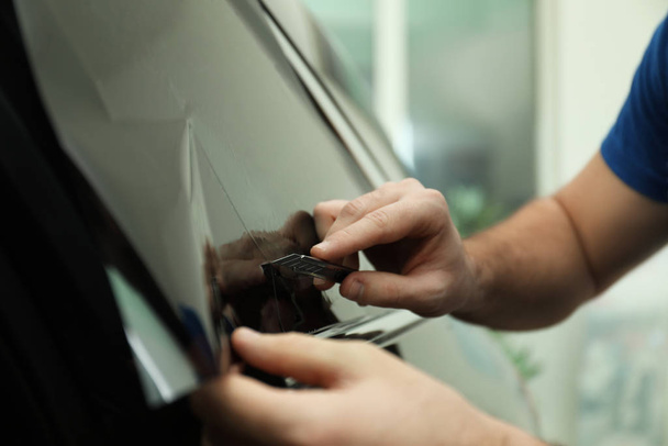 Worker tinting car window with foil in workshop, closeup - Photo, image