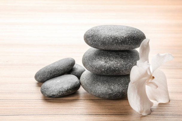 Stones and orchid flower on wooden background. Zen lifestyle - Photo, Image