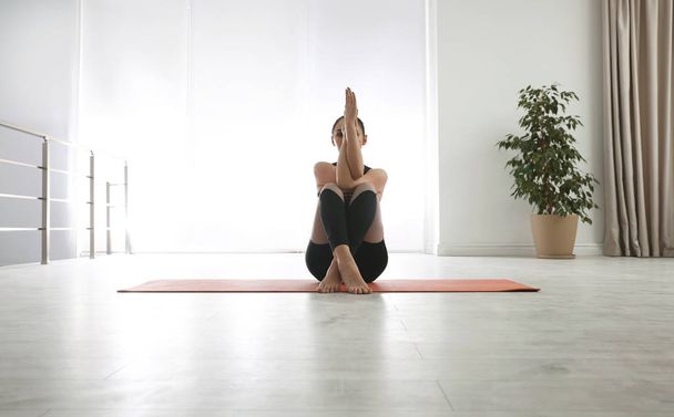 Woman practicing eagle asana in yoga studio. Garudasana pose - Φωτογραφία, εικόνα