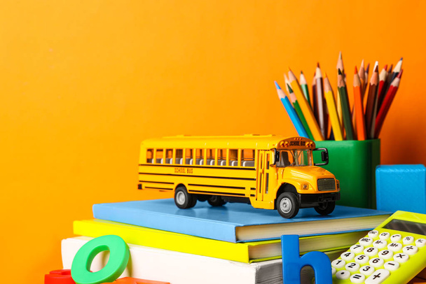 School bus model and stationery on orange background. Transport  - Foto, afbeelding