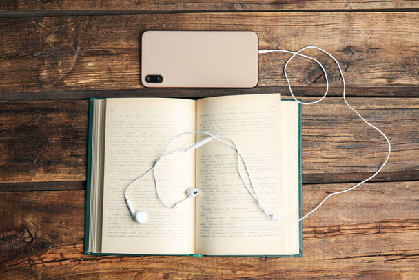 Book, headphones and smartphone on wooden table, flat lay - Foto, afbeelding