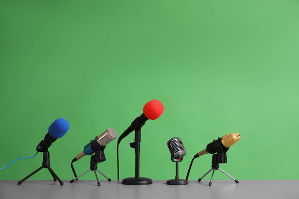 Microphones on table against green background. Journalist's work - Φωτογραφία, εικόνα