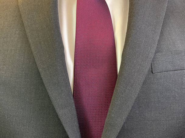 Ένας άντρας με κοστούμι και γραβάτα, από κοντά. Ένας επιχειρηματίας φοράει σκούρο γκρι σακάκι και λευκό πουκάμισο. Έννοια: ενδυματολογικός κώδικας, εμφάνιση - Φωτογραφία, εικόνα