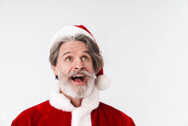 Image of gray-haired Santa Claus old man in red costume looking  - Fotó, kép
