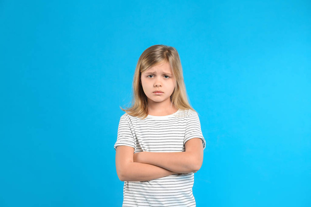 Upset little girl on light blue background - Φωτογραφία, εικόνα
