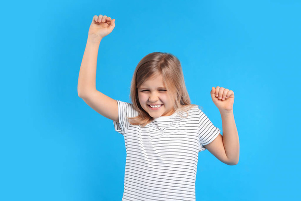 Excited little girl on light blue background - Фото, изображение