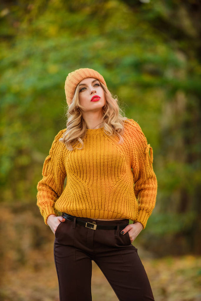 Feeling the nature. autumn color trend. beautiful fashion model in knitwear sweater and hat. feeling romantic in fall forest. sexy woman red lipstick nature background. warm and cosy seasonal clothes - Photo, Image